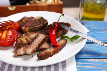Roasted beef fillet and grilled vegetables on plate, on wooden background