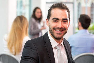 Young attractive businessman working at the office with associat