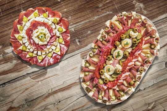 Two Platters of Savory Antipasto Meze Appetizers, Placed on Old Lacquered, Peeled-off Varnished Wooden Garden Table Surface.