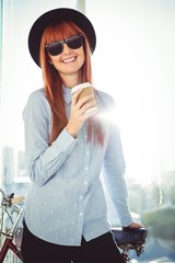Smiling hipster woman leaning on a bike
