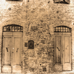 wooden doors in a brick wall in San Gimignano in sepia tone