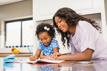 Young girl doing her homework with her mother 