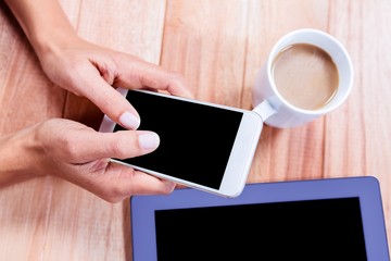 Businesswoman using her smartphone on desk