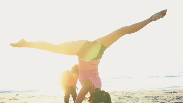mother does gymnastics with her child on the beach slow motion