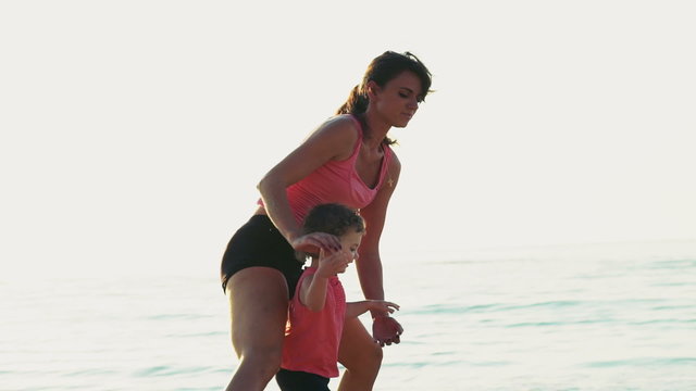 mother does gymnastics with her child on the beach slow motion