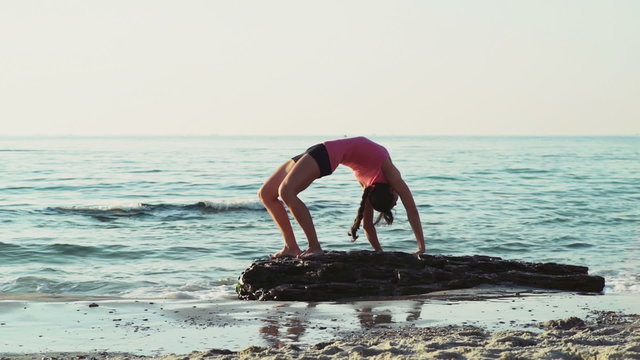 young female does gymnastics on the beach slow motion