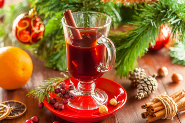 Holiday winter hot drink. Mulled wine with fruits and spices by Christmas tree with decorations.