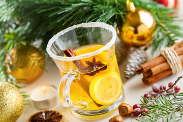 Fototapeta na wymiar Holiday winter hot citrus drink near Christmas tree with decorations. Lemon tea.