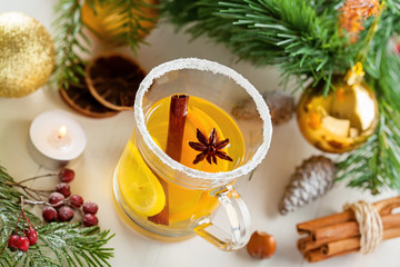 Glass of mulled cider by Christmas tree with decorations. Traditional hot drink. Top view.