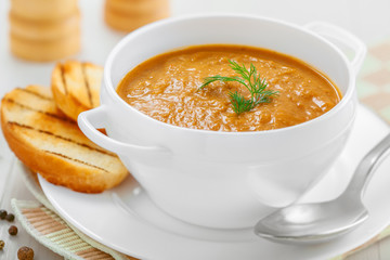 Lentil cream soup with toasts on white table
