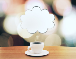 Cup of coffee with speech bubble in the form of cloud on wooden