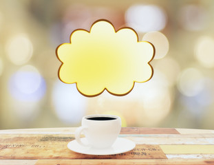 Cup of coffee and speech bubble in the form of cloud on wooden t