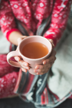 Young woman relaxing in bed with a cup of tea