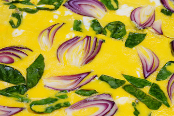 Omelette with blue onion and spinach on parchment. View from above, top studio shot