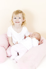 portrait of a little girl cradling her one month old baby sister