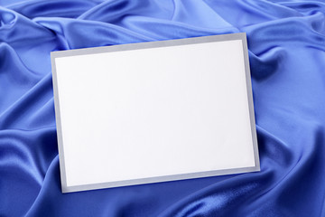 Naklejka premium Blank greetings card or invitation with blue satin background.