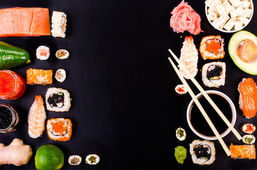 Fototapety  Zestaw sushi, sos sojowy, imbir, wasabi na czarnym tle. Wolne miejsce na Twój tekst. Ramka do żywności