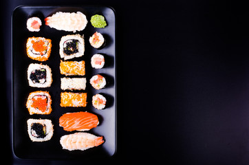 Sushi set, soy sauce, ginger, wasabi on black background. Free space for your text. Food frame