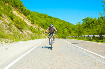 Male cyclist riding a bike on mountain road