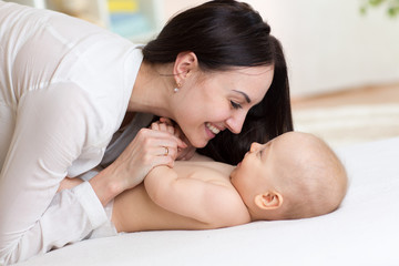 Happy mother playing with baby in bedroom