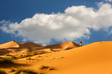 Fototapeta na wymiar Woman walks through the dunes of Sahara Desert , Morocco