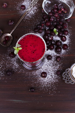 Frozen summer berries smoothie garnished with mint on dark wooden background. View from above, top studio shot