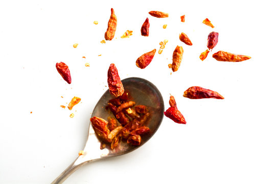 dried chili peppers jumping from a spoon, isolated on white, hea