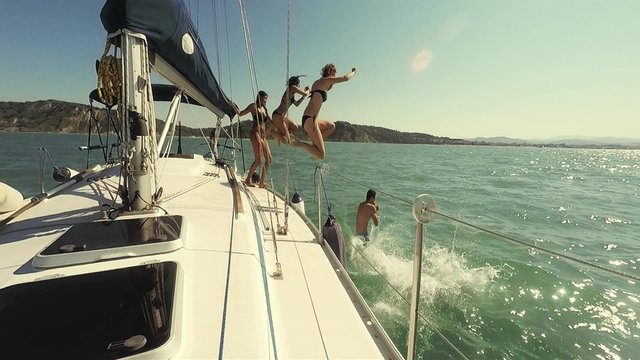 Group of friends jumping from the boat