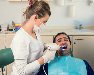 Dentist and her patient. He is showing pain at the procedure