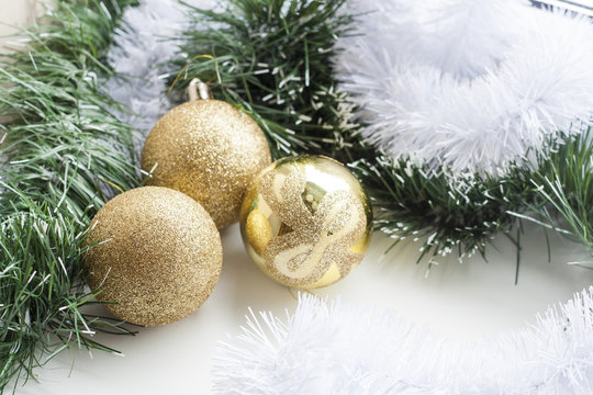 Gold decorative Christmas ball and green and white garland on white background