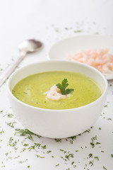 a bowl of  green cream soup and shrimps