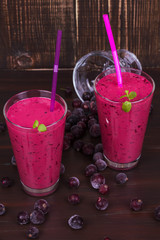 Frozen summer berries smoothie garnished with mint on dark wooden background