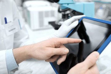 close up of scientists hands with tablet pc in lab