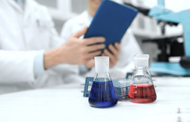 Fototapeta premium close up of scientists with flasks and tablet pc