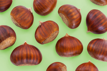 Texture of many chestnuts on green background, autumn decoration