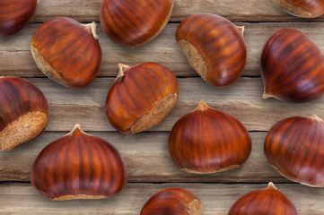 Texture of many chestnuts on wood background, autumn decoration