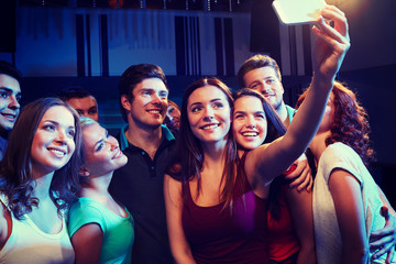 friends with smartphone taking selfie in club
