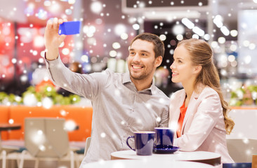 happy couple with smartphone taking selfie in mall