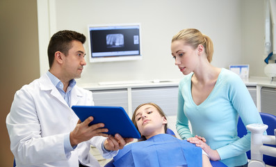 Obraz premium dentist showing tablet pc to girl and her mother