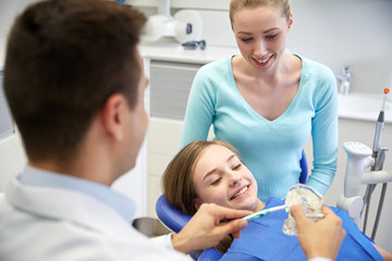 happy dentist showing toothbrush to patient girl