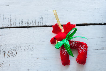 Santa Claus Christmas reindeer - red toy with green bow, on white wooden background, empty space...