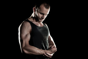 muscular man,  clasps hands in  fist, black background, place for text on the right