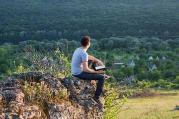 Naklejka premium man sitting on the edge of a cliff with book