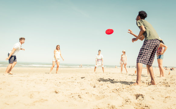 Group of friends playing with frisbee on the beach