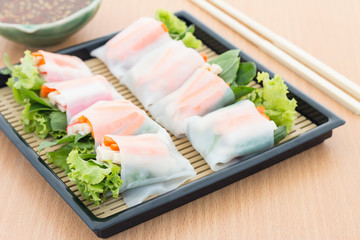 Vegetables in noodle tube with spicy sauce on wooden plate
