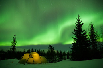 beleuchtetes Zelt mit Nordlichtern im Hintergrund 