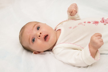 The surprised baby lying on white towel