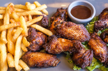 Chicken wings with sauce and golden French fries potatoes