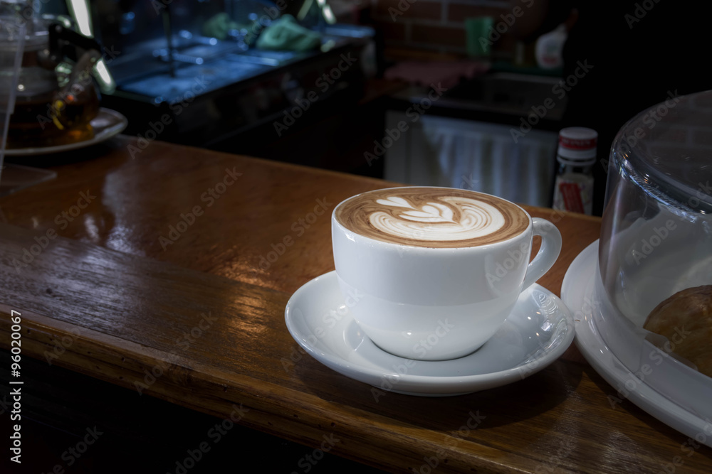 Wall mural close up white cup of coffee, latte on the wooden table