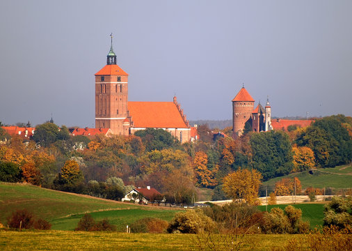 Red brick medieval church and castle in Reszel, Poland. Wide sunny view. Autumn season.
